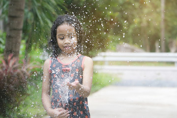 Happy Asian little child girl having fun to play with water in garden with copy space 