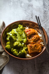 Thai salmon dish in coconut sauce with fresh broccoli and rice in a clay bowl with chopsticks . healthy food with vitamin B5...