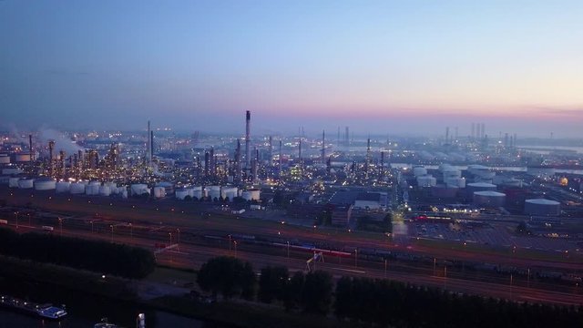 Aerial view of twilight of oil refinery , shot with drone. Oil refinery and Petrochemical plant at dusk . Wind mill visible. Shot in Pernis Rotterdam.