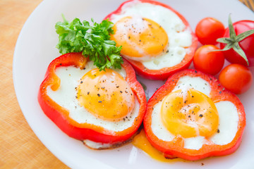 Fototapeta na wymiar fried eggs in red peppers in a plate close-up. horizontal view from above