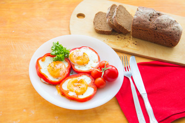 Fried eggs in paprika served on white plate on wooden background