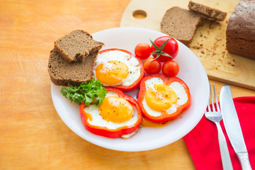 Fried eggs in red peppers. Fried eggs in paprika served on white plate on wooden background