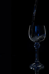 Wine in beautiful vintage crystal glasses on black wall background, with copy space. Wine list, bar drink menu, wine boutique or degustation, square crop concept. Water is poured into a glass