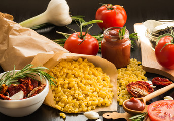 Ingredients. Pasta with Fresh tomatoes, Sun-dried tomatoes and Tomato Sauce on dark background. Cooking concept. Italian cuisine