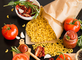 Ingredients. Pasta with Fresh tomatoes, Sun-dried tomatoes and Tomato Sauce on dark background. Cooking concept. Italian cuisine