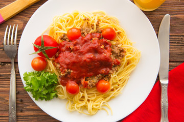 Spaghetti bolognese with tomatoes on a wooden background
