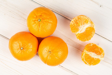 Group of three whole two halves of fresh orange mandarine flatlay on white wood