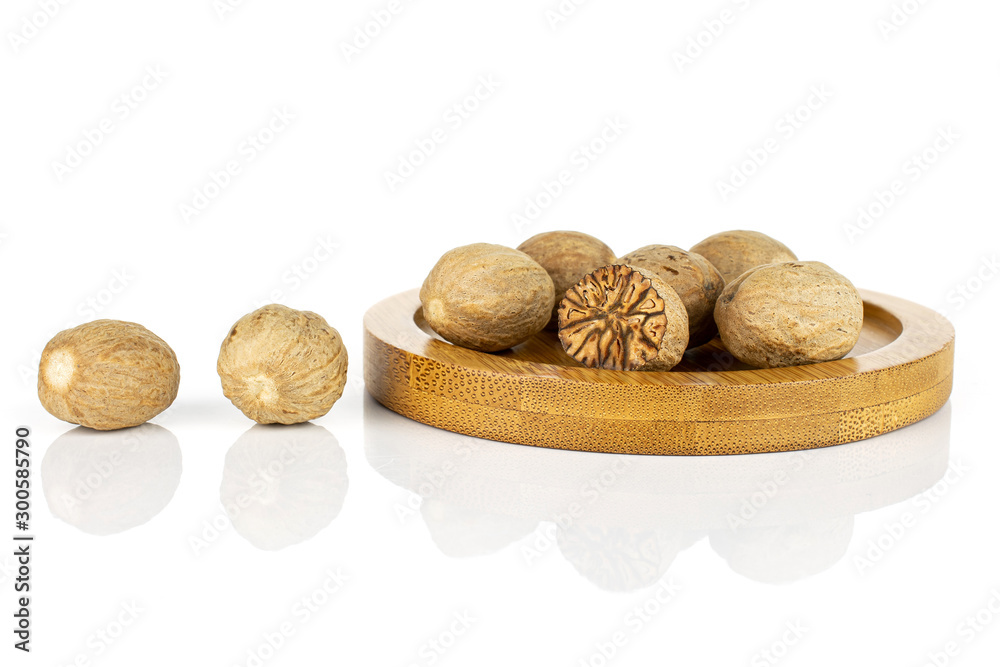 Wall mural lot of whole one half of dry brown nutmeg on bamboo coaster isolated on white background