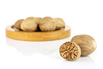 Lot of whole one half of dry brown nutmeg on bamboo coaster isolated on white background