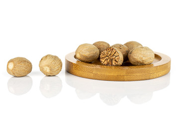 Lot of whole one half of dry brown nutmeg on bamboo coaster isolated on white background