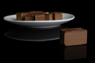 Lot of whole sweet brown viennese nougat on white ceramic plate isolated on black glass
