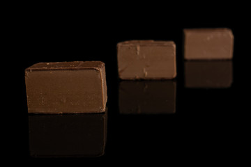 Group of three whole sweet brown viennese nougat placed diagonally isolated on black glass