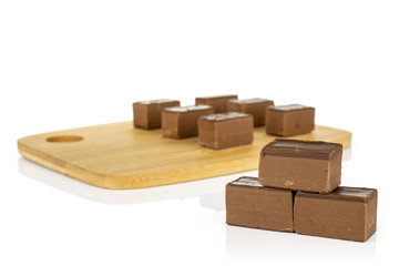 Group of nine whole sweet brown viennese nougat on bamboo cutting board isolated on white background