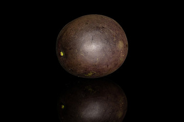 One whole sweet dark purple passion fruit isolated on black glass