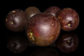 Group of five whole sweet dark purple passion fruit isolated on black glass