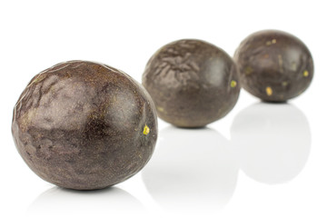 Group of three whole sweet dark purple passion fruit placed diagonally isolated on white background