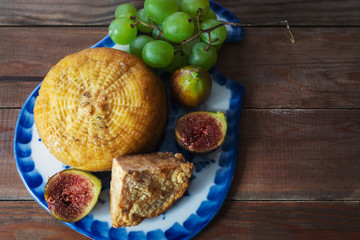 cheese, figs, grapes and knife on cutting board
