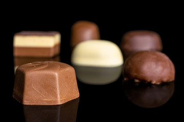 Group of six whole delicious chocolate praline isolated on black glass
