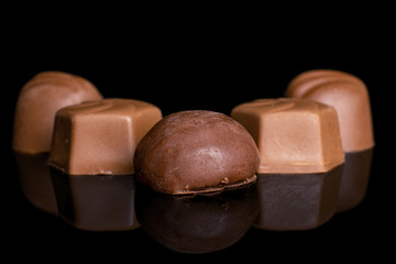 Group of five whole delicious chocolate praline isolated on black glass