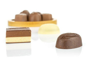 Group of eight whole delicious chocolate praline on bamboo coaster isolated on white background