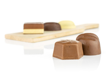 Group of five whole delicious chocolate praline on small wooden cutting board isolated on white background