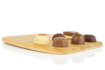 Group of six whole delicious chocolate praline on bamboo cutting board isolated on white background