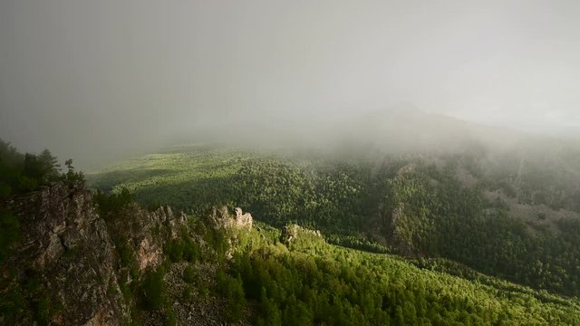 Panoramic view of senic green valley covered by forest with drifting low clouds