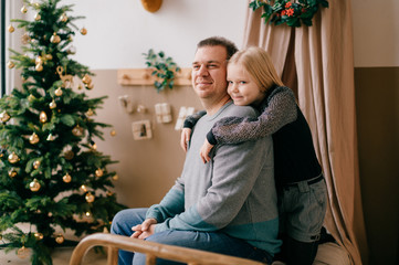Happy father and lovely daughter hugs each other in zoy room with cristmas tree and children wigwam. New year holidays.
