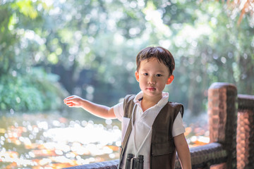 A boy is feeding koi at the river