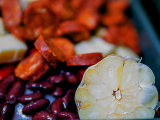 Mexican style dish with onion, cheese, garlic, beans, chorizo, red chilly peppers. Preparation stage, close up.
