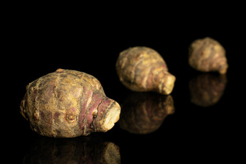 Group of three whole fresh brown jerusalem artichoke isolated on black glass