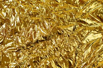 Gold leaf background texture with shiny crumpled uneven surface