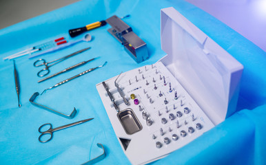 Set of dentist tools on blue background: dentist mirror, forceps curved, explorer curved, dental explorer angular and explorer curved with chip, right. Dental Hygiene and Health concept.
