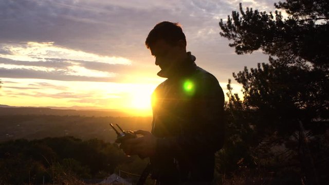 A man controls his quadcopter, images at sunset. The glare of the sun.The average plan