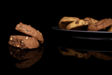 Lot of whole sweet brown cookie on gray ceramic plate isolated on black glass