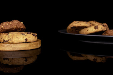 Lot of whole sweet brown cookie on gray ceramic plate isolated on black glass