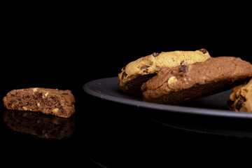 Group of three whole one half of sweet brown cookie on gray ceramic plate isolated on black glass