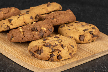 Group of seven whole sweet brown cookie on bamboo cutting board flatlay on grey stone