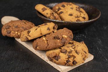 Group of six whole sweet brown cookie in glazed bowl on wooden cutting board flatlay on grey stone