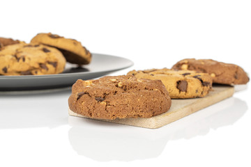 Group of six whole sweet brown cookie on gray ceramic plate on wooden cutting board isolated on white background
