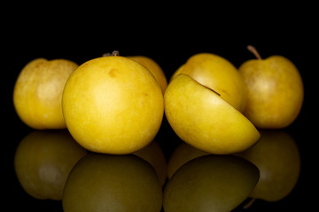 Group of five whole one half of fresh yellow plum isolated on black glass