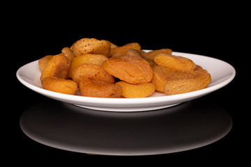 Lot of whole dried orange apricot on white ceramic plate isolated on black glass