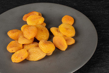 Lot of whole dried orange apricot on gray ceramic plate on grey stone