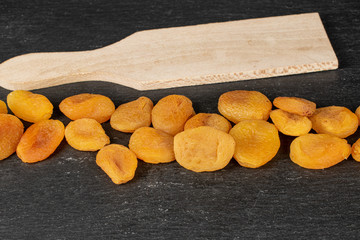 Lot of whole dried orange apricot on wooden cutting board on grey stone