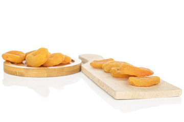 Lot of whole dried orange apricot on wooden cutting board isolated on white background