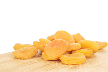Lot of whole dried orange apricot stack on bamboo cutting board isolated on white background