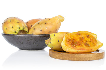 Group of three whole two halves of prickly green opuntia in glazed bowl on round bamboo coaster isolated on white background