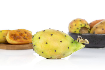 Group of four whole two halves of prickly green opuntia in glazed bowl on round bamboo coaster isolated on white background