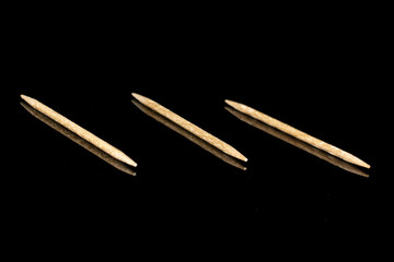Group of three whole wooden brown toothpick isolated on black glass