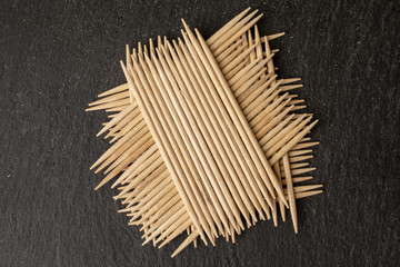Lot of whole wooden brown toothpick heap flatlay on grey stone